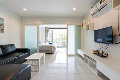 a living room with a couch and a television at The Pixels Cape Panwa Condo in Ban Ao Makham