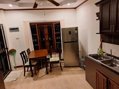 a kitchen with a table and a stainless steel refrigerator at Garden & private pool house in Surin Beach