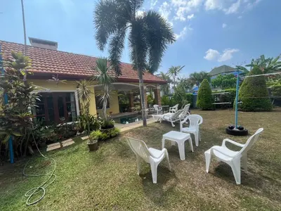 a yard with white chairs and a house with a palm tree at Garden & private pool house in Surin Beach