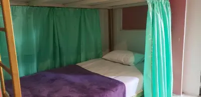 a small bed in a room with green curtains at Lucky Dorm in Phi Phi Don