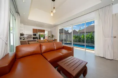 a living room with a brown leather couch and a kitchen at Bangtao Beach Villa with a Long pool 12 meters in Phuket Town