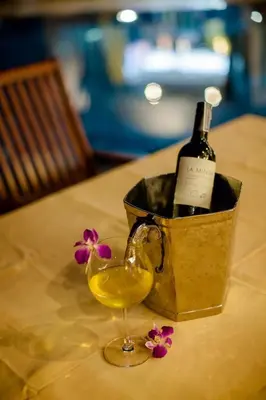 a bottle of wine and a glass with flowers on a table at Villa REGTUK in Patong Beach