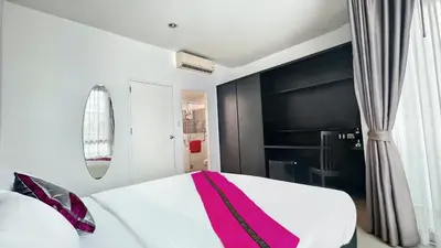 a bedroom with a white bed with a pink blanket at Vi Stay in Phuket Town