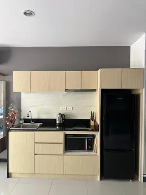 a kitchen with wooden cabinets and a black refrigerator at Nai Harn Beach Condo (C2) in Rawai Beach