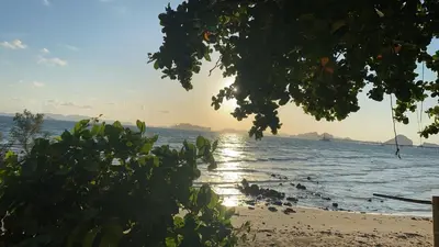 a beach with the sun shining on the water at Green Tree Cottage3 in Klong Muang Beach