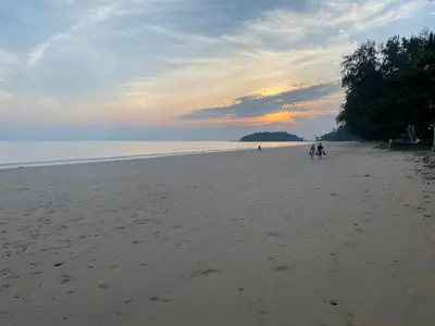 a group of people walking on the beach at sunset at Green Tree Cottage 4 in Klong Muang Beach
