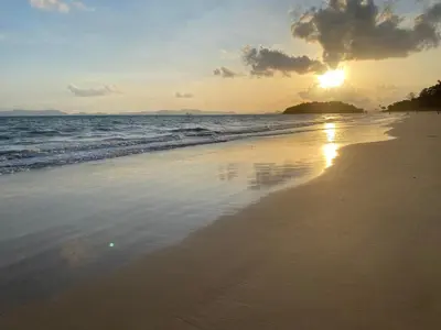a sunset on a beach with the sun setting at Green Tree Cottage 4 in Klong Muang Beach