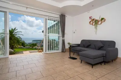 a living room with a couch and a large window at Villa Olympus Ocean Vista Kata Beach in Kata Beach