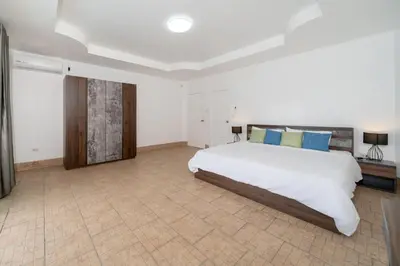 a large bedroom with a white bed and blue pillows at Villa Olympus Ocean Vista Kata Beach in Kata Beach