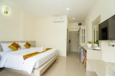 a bedroom with a large white bed and a bathroom at Puean Chang Resort Phuket in Thalang
