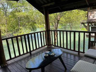 a wooden porch with a coffee table on a deck at Ban Tha Ton Do Koh Yao noi in Ko Yao Noi