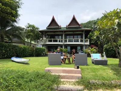 two people sitting at a table in front of a house at Bali style 4 bedroom beachfront Villa Ao Yon in Ban Ao Makham