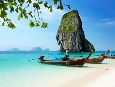 two boats on a beach with a rock in the water at OYO 1148 Aonang Andaman Resort in Ao Nang Beach