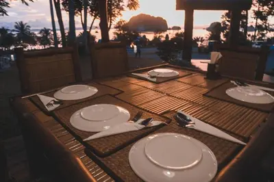 a wooden table with white plates and silverware on it at Khaothong Terrace Resort in Ban Khao Thong