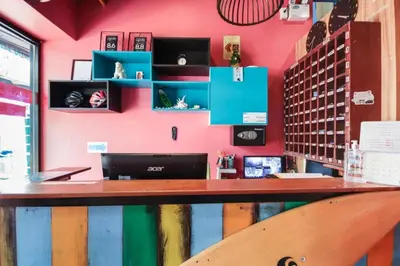 a pink wall with a wooden counter in a restaurant at OYO 1074 Fin Hostel in Kata Beach