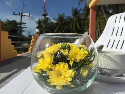 a glass vase filled with yellow flowers on a table at The Royhanna Beach House in Tab Kaek Beach