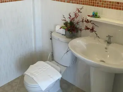 a white bathroom with a toilet and a sink at The Royhanna Beach House in Tab Kaek Beach