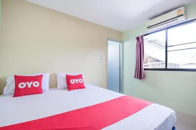 a bedroom with a large white bed with red pillows at OYO 1163 Eden Hostel in Phuket Town