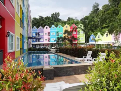 a pool in front of a colorful building at Holland Resort Phuket in Ban Phlu Yai