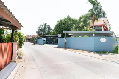 an empty street with a blue fence and trees at OYO 732 Juthamas Hotel in Ban Nai