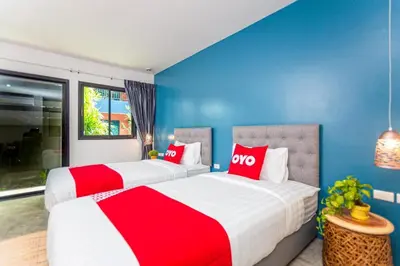 two beds in a room with blue and red at OYO 422 Jane Homestay and Resort in Ban Kata