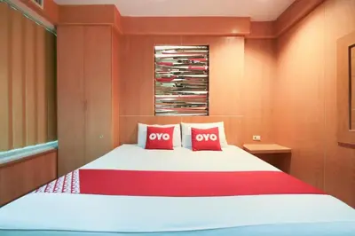 a bedroom with a large bed with two red pillows at OYO 1172 Goodnight Resort in Phuket Town