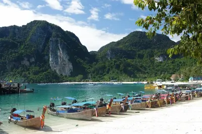 a group of boats parked on a beach at Phuttachot Resort in Phi Phi Don