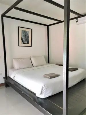 a bedroom with a white bed with a black frame at Natai House Resort นาใต้เฮ้าส์ รีสอร์ท in Natai Beach