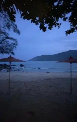 two umbrellas sitting on a beach at night at Lakshmi beach house in Phuket Town