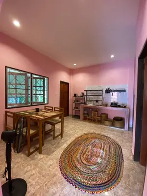 a living room with a table and a kitchen at Lakshmi beach house in Phuket Town