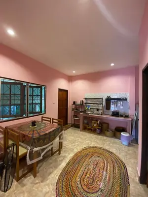 a living room with a table and a room with pink walls at Lakshmi beach house in Phuket Town