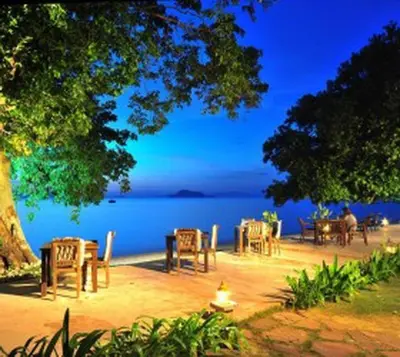 a group of tables and chairs next to the water at Blue Koh Yao Yai Resort and Villa in Ko Yao Yai