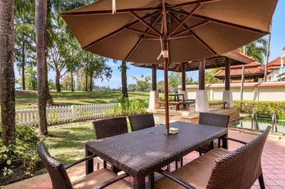 a table and chairs with an umbrella on a patio at Laguna Fairway View Villa in Bang Tao Beach