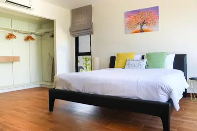 a bedroom with a bed with white sheets and colorful pillows at Super Friendly TH Laguna Park in Phuket Town