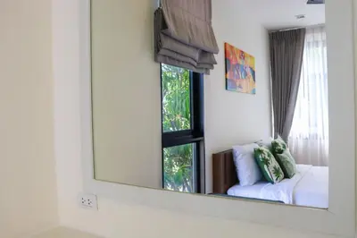 a mirror in a room with a couch and a window at Super Friendly TH Laguna Park in Phuket Town