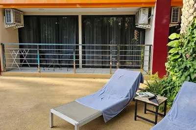 a bed and a table in front of a building at Новая квартира с выходом к бассейну in Mai Khao Beach