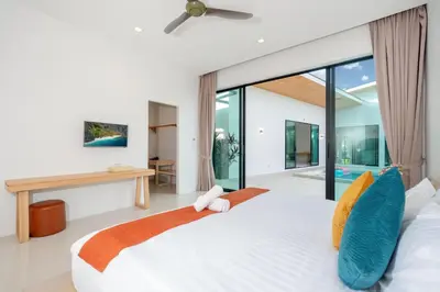 a bedroom with a large white bed with blue pillows at Garden pool villa V110 in Kata Beach