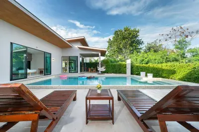 a swimming pool in a house with two benches at Garden pool villa V110 in Kata Beach