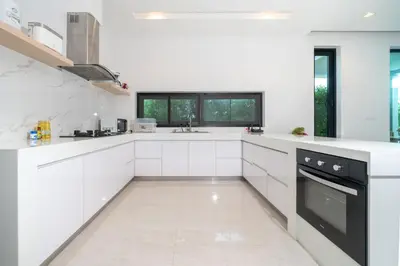 a white kitchen with white cabinets and black appliances at Garden pool villa V110 in Kata Beach