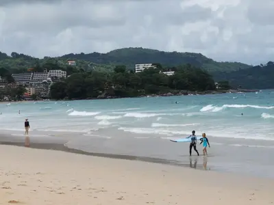 a man and two children walking on the beach with a surfboard at 7 Floor - Studio Room at TBHR near Kata beach in Kata Beach