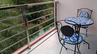 a balcony with two chairs and a view of a garden at Rawai Beach Condo by Holy Cow in Nai Harn Beach