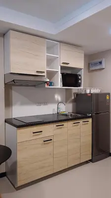 a kitchen with wooden cabinets and a stainless steel refrigerator at Rawai Beach Condo by Holy Cow in Nai Harn Beach