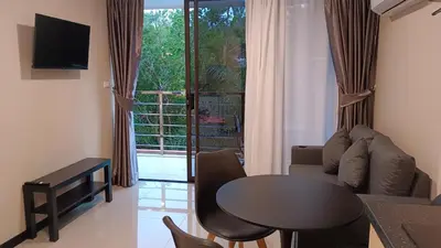 a living room with a table and a couch and a window at Rawai Beach Condo by Holy Cow in Nai Harn Beach