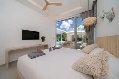 a white bedroom with a large bed and a tv at Tropical Brand New 4BR Pool Villa Mina, just 5 min Drive from Naiharn in Rawai Beach