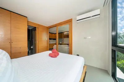 a bedroom with a bed with a pink stuffed animal on it at Tropics Kamala Corner Studio CTG D309, 3 Pools & Gym, near Beach in Kamala Beach