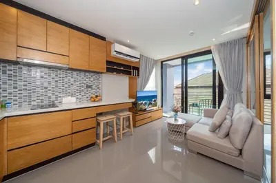 a living room with a couch and a kitchen at Tropics Kamala Corner Studio CTG D309, 3 Pools & Gym, near Beach in Kamala Beach