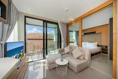 a living room with a couch and a bed and a television at Tropics Kamala Corner Studio CTG D309, 3 Pools & Gym, near Beach in Kamala Beach
