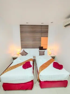 a bedroom with two beds with red and white sheets at Patong Max Value Hotel in Patong Beach