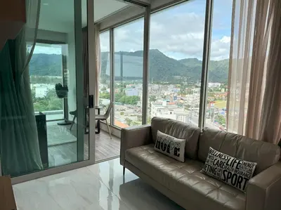 a living room with a couch and large windows at Apartment with panoramic views at Oceana by Lofty in Kamala Beach