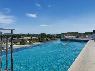 a person swimming in a large swimming pool at 7 Floor - Mountain view Studio room at OZC near Kata beach in Kata Beach